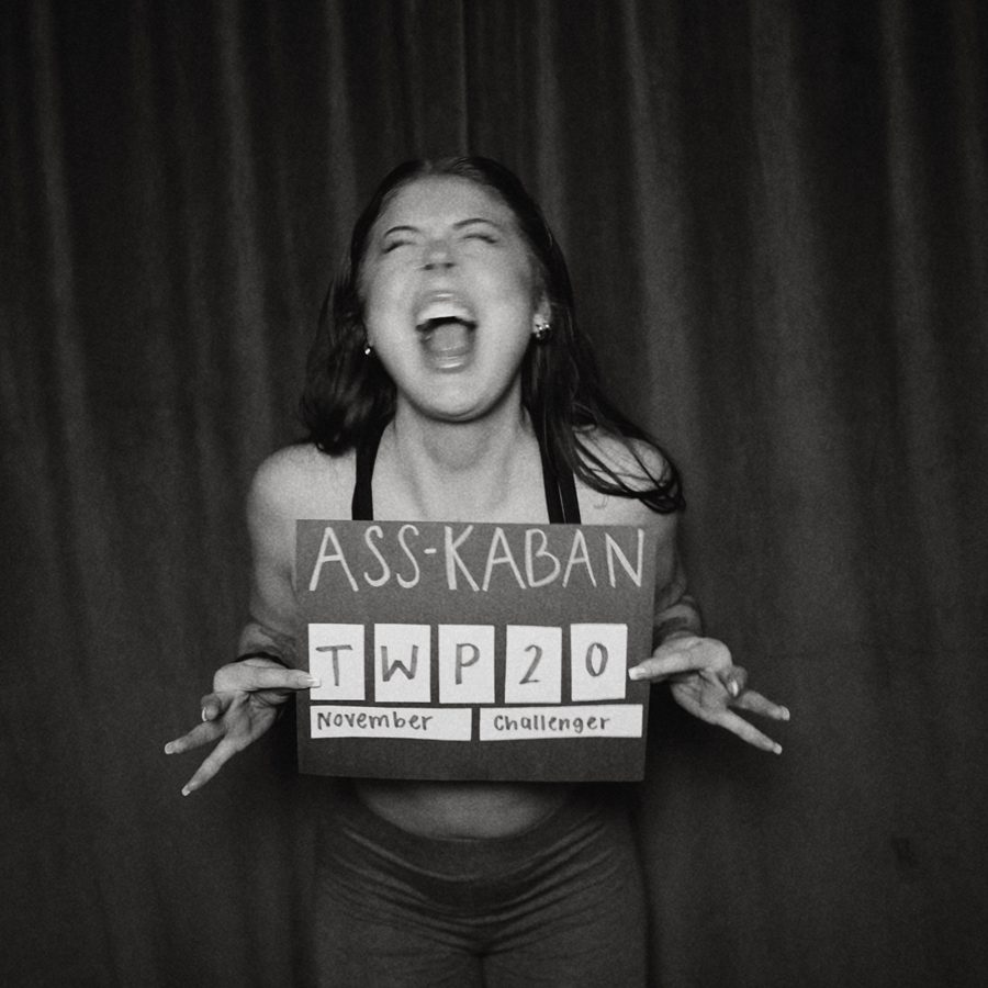 Black and white mugshot-style photo holding an ASS-KABAN November challenge sign