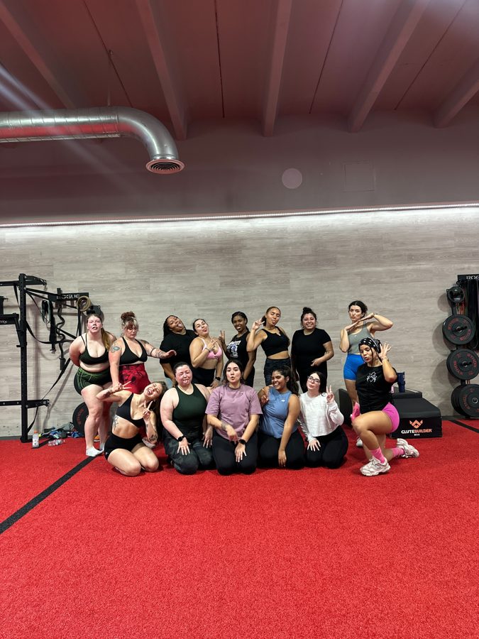 Group photo on the red gym floor after a community workout class