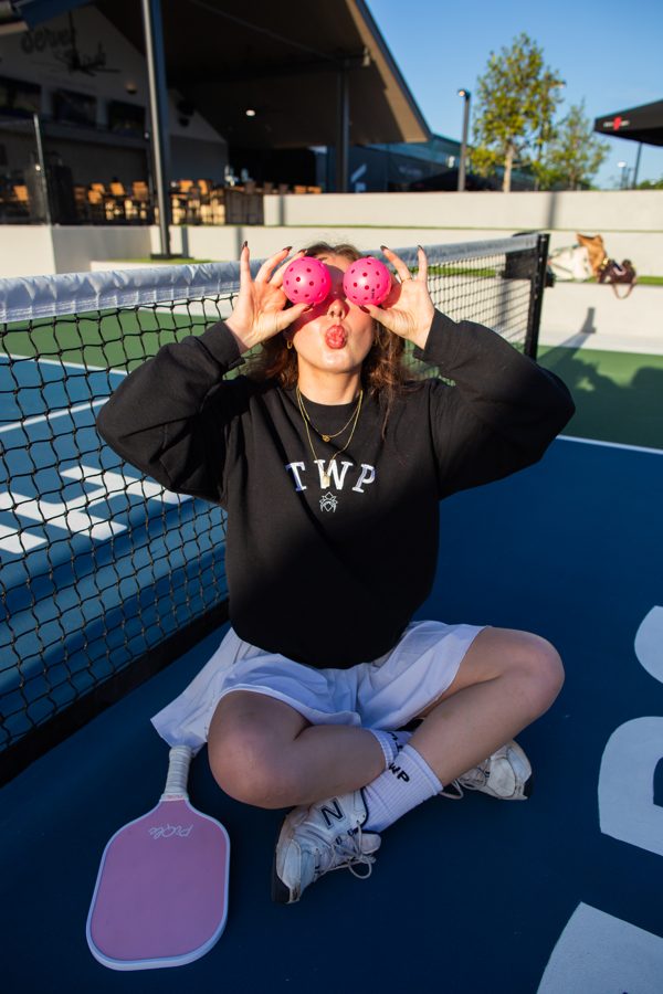 TWP crewneck and pickleballs held over eyes at a community event